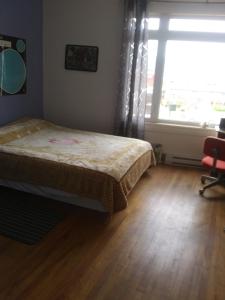 a bedroom with a bed and a large window at Appartement centre ville de Campbellton NB in Campbellton