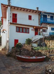 a house with red windows and a boat in front of it at La casina de Marga in Villaviciosa
