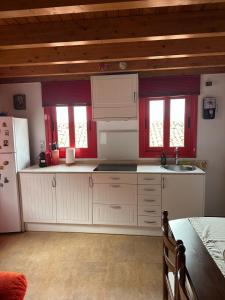 a kitchen with white cabinets and red windows at La casina de Marga in Villaviciosa