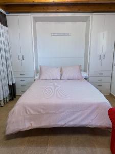 a bedroom with a large bed with pink pillows at La casina de Marga in Villaviciosa
