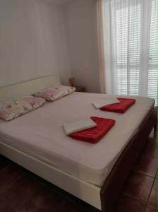 a white bed with two red towels on it at Apartments Vera in Ližnjan