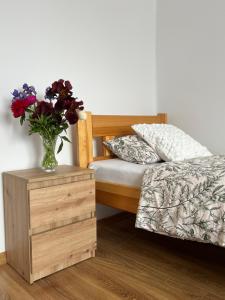 a vase of flowers on a night stand next to a bed at Wakacje u Dziadków in Ruciane-Nida