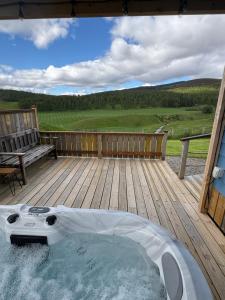 a hot tub on a wooden deck with a bench at Ledmacoy Shepherds Huts in Strathdon