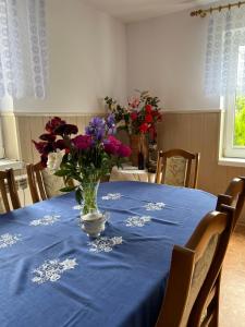 a table with a blue table cloth with a vase of flowers at Wakacje u Dziadków in Ruciane-Nida