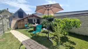 a table and chairs and an umbrella in a yard at Le Cosy Houdan in Goussainville