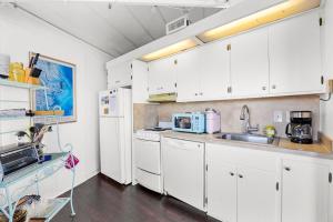 a kitchen with white cabinets and a sink and a refrigerator at 8951 - Ozzie's Island Hideaway in Hatteras