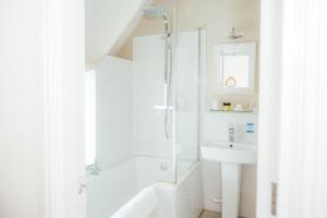 a white bathroom with a shower and a sink at The Cott Inn in Totnes +70 photos