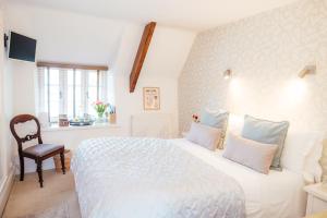 a bedroom with a large white bed and a chair at The Cott Inn in Totnes