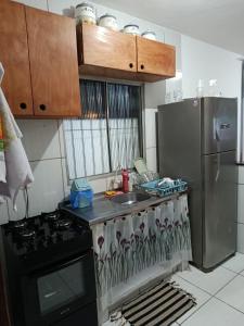 a kitchen with a stove and a sink and a refrigerator at Jacumã Beach House in Conde