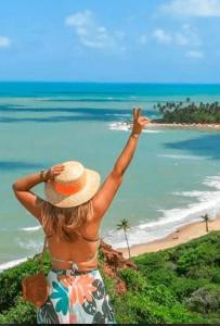 a woman in a hat looking at the ocean at Jacumã Beach House in Conde
