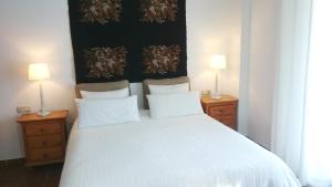 a bedroom with a white bed with two lamps at APARTAMENTOS LA MUNDIAL - Alojamiento en Málaga capital in Málaga