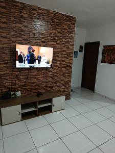 a television on a brick wall in a room at Jacumã Beach House in Conde