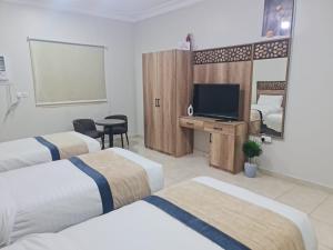 a hotel room with three beds and a flat screen tv at شقق مفروشة مكين 1 in Medina