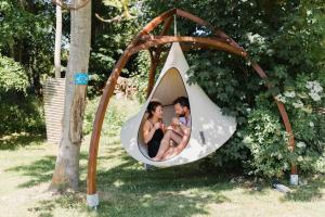 a man and a woman and a baby in a swing at La Bulle au bord de l'eau in Épagne-Épagnette