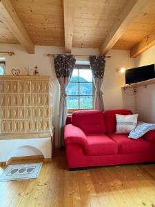 a living room with a red couch and a window at Villetta Ximenes in Panchià