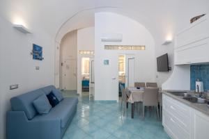 a living room with a blue couch and a kitchen at Grecale - stunning sea-view apartment with patio, up to 5 guests in Maiori