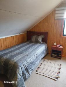 a bedroom with a bed and a wooden wall at Casa Halcon de Lagunitas in Puerto Montt