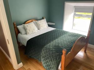 a bedroom with a bed with a green comforter and a window at Old lake house in Gortatlea