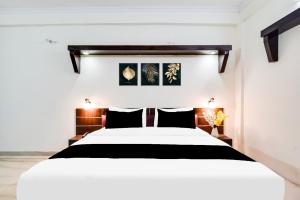 a bedroom with a white bed with black pillows at HOTEL O 4 SQUARE A LUXURY ROOMS NEAR RDC MAIN MARKET in Ghaziabad