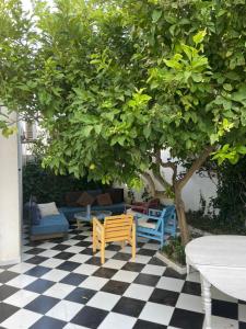 a table and chairs under a tree on a checkered floor at SecretVilla in Ghār al Milḩ +1 photo