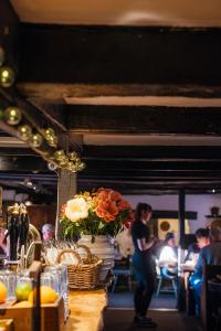 a woman standing behind a table with a vase of flowers at The Cott Inn in Totnes