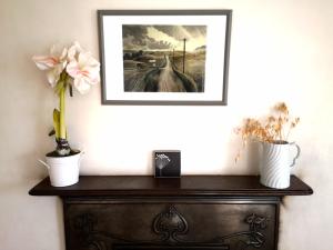 a picture on top of a dresser with flowers on it at Priory Cottage Castle Acre in Castle Acre