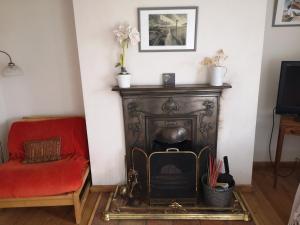 a living room with a fireplace and a red couch at Priory Cottage Castle Acre in Castle Acre