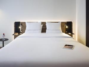 a large white bed with white sheets and pillows at Novotel Lausanne Bussigny in Lausanne +132 photos