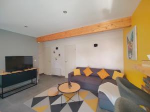 a living room with a couch and a tv at À la Volette - Cosy, Nature & Miel des Vosges in Plombières-les-Bains