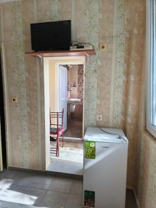 a room with a refrigerator and a television on a wall at Дом Колеви in Chernomorets
