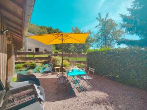 a patio with a table and a yellow umbrella at À la Volette - Cosy, Nature & Miel des Vosges in Plombières-les-Bains