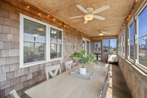 a porch with a ceiling fan and a table and chairs at 8055 - Down By The Dunes in Rodanthe