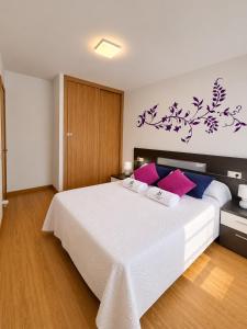 a bedroom with a large bed with purple and blue pillows at O LAR DE MARTINA in Redondela