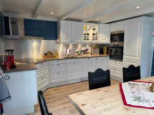 a kitchen with white cabinets and a wooden table at Horgheim Boutique Lodge, Romsdalen in Åndalsnes