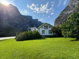 a house on a grassy field with a mountain in the background at Horgheim Boutique Lodge, Romsdalen in Åndalsnes
