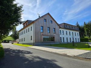 a large wooden building on the side of a road at AVA apartmán Javorná na Šumavě in Čachrov