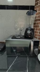 a blender and two wine glasses on top of a microwave at Casa Inteira com Garagem, no Goiabal até 3 hospedes in Macapá