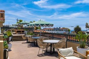 a patio with tables and chairs on a balcony at The Mara Laguna Beach, an AvantStay Hotel in Laguna Beach