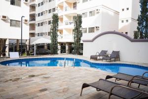 a swimming pool with two benches next to a building at Vossa Bossa Olimpia in Olímpia