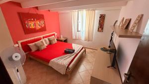 a small bedroom with a red bed with a red blanket at Attico Residence Costa do Sol in Sal Rei
