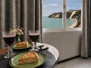 a table with two plates of food and two glasses of wine at Flat vista Mar -conforto e estilo em Ponta Negra-Natal in Natal