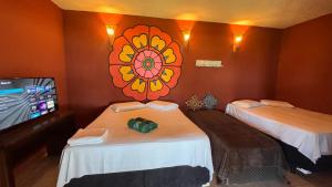 a room with two beds and a television with a flower on the wall at Suítes icarai vila in Caucaia
