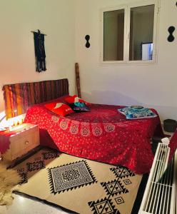 a bedroom with a bed with a red blanket and a window at Dar D'Art in Tunis