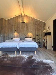 a bedroom with two beds and a wooden wall at Chalet de Mielandre in Vesc