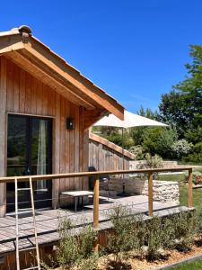 a wooden cabin with a deck with an umbrella at Chalet de Mielandre in Vesc