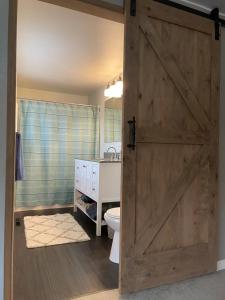 a bathroom with a wooden door with a toilet and a sink at Gravel Road Getaway in Hermiston