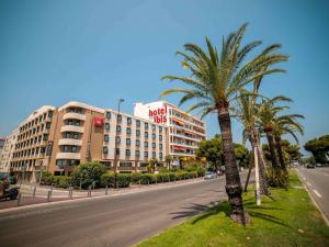 a palm tree on the side of a street with a hotel at ibis Nice Aéroport Promenade des Anglais in Nice