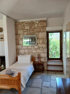 a bedroom with a bed and a stone wall at Egina Home in Egina