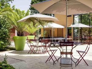 a group of tables and chairs with umbrellas at ibis Lyon Nord in Dardilly