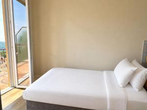 a bedroom with a white bed and a large window at Panorama - Lake Maggiore House in Colazza